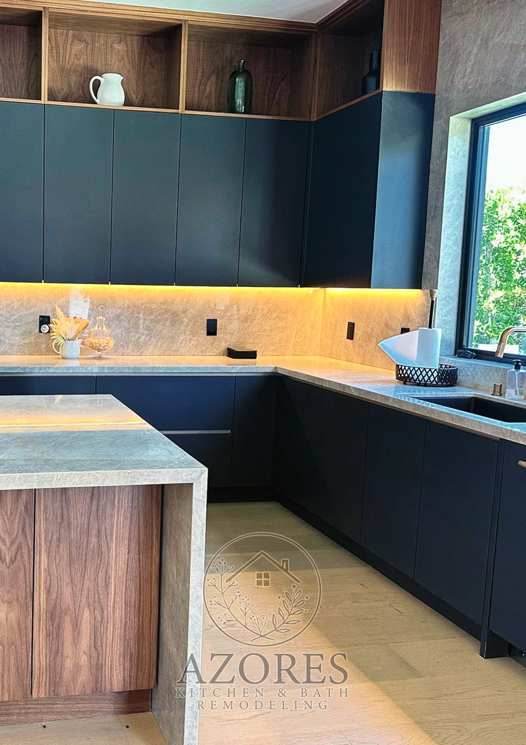 Modern kitchen with sleek black cabinets, a marble countertop, and stainless steel appliances.