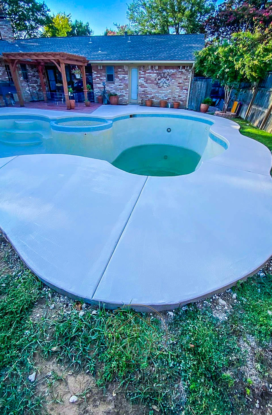 Renovated poolside area with non-slip stone flooring, lounge chairs, and modern landscaping.